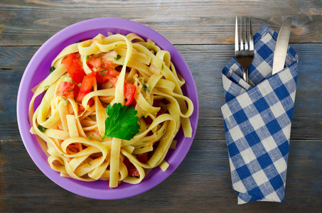 盘子里的意大利面。 意大利面条，西红柿，洋葱，卷心菜，木制背景