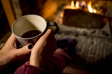 女人正在壁炉里取暖，而她正在喝咖啡