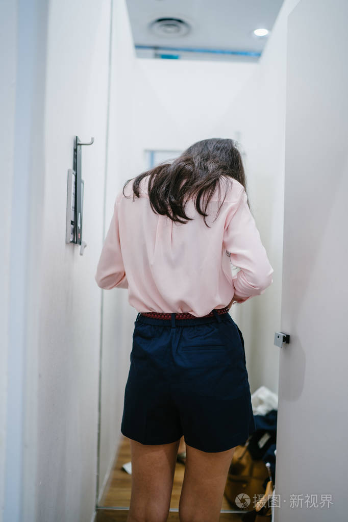 一位年轻美丽的印度亚洲妇女在商场时装店的试衣间试穿新衣服的肖像.