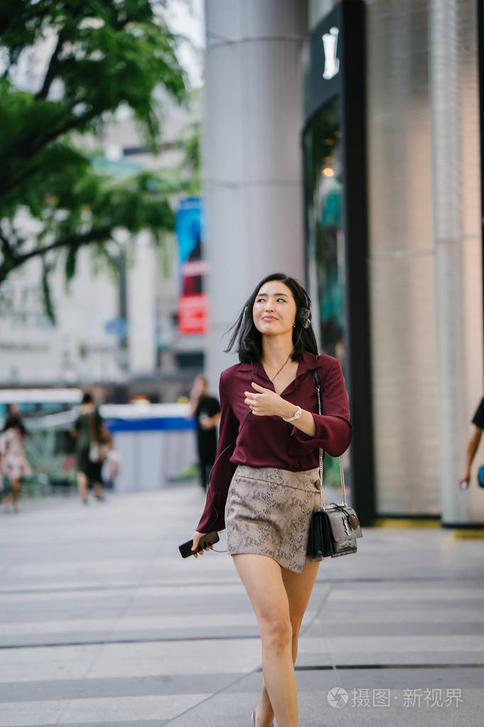美丽的韩国女人穿着优雅的衬衫和短裤跳舞她走在城市的一条街上戴着