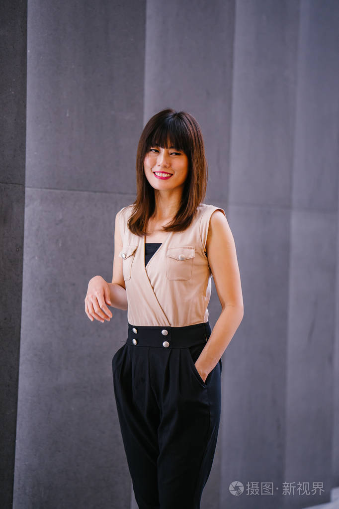 年轻的中国亚裔女性站在亚洲购物中心外面,背景是购物中心