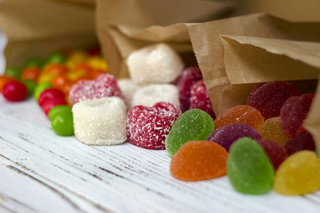 圆形彩色糖果和果酱放在木桌上的纸袋里，明亮的糖果，白色的背景