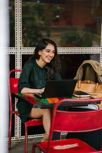 年轻的大学生印度亚裔女性白天在餐桌上学习和工作她的笔记本电脑