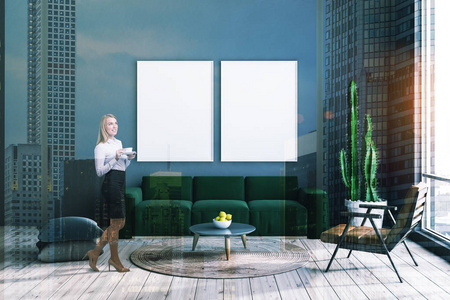 女士在灰色客厅内部，轻木地板，绿色沙发和皮革扶手椅附近的圆形咖啡桌和两个垂直海报。 色调图像双曝光模拟