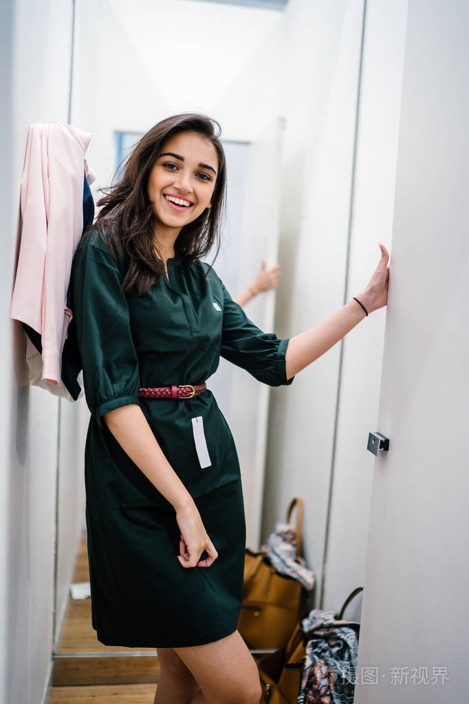 一位年轻美丽的印度亚洲妇女在商场时装店的试衣间试穿新衣服的肖像