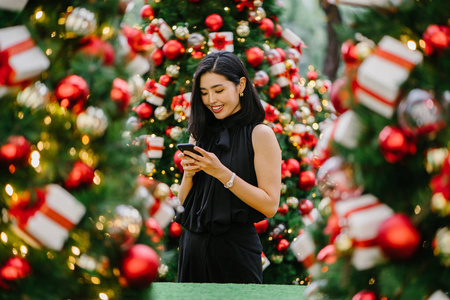一位美丽年轻的韩国亚裔妇女的肖像，她在看到圣诞装饰时微笑，并为之惊叹