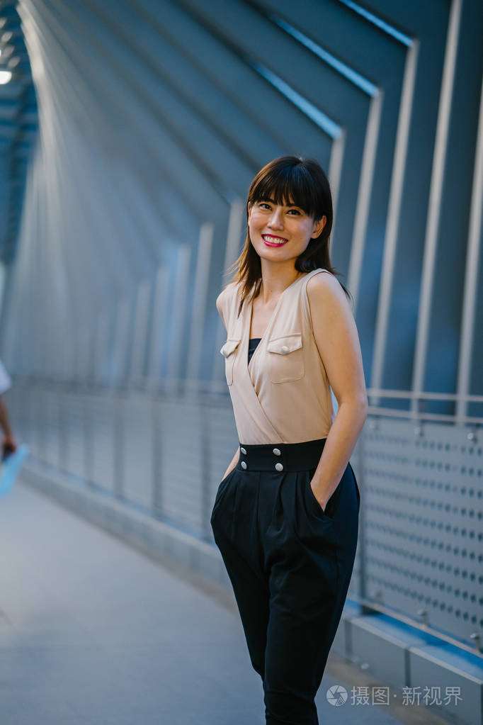 年轻的中国亚裔女性站在亚洲购物中心外面,背景是购物中心