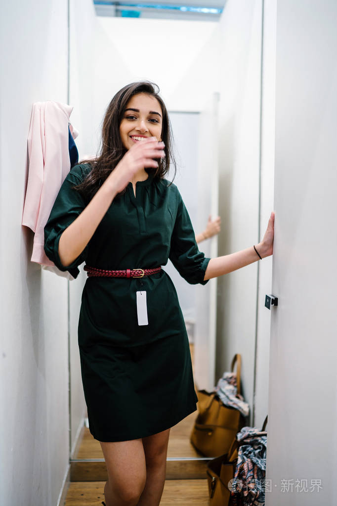 一位年轻美丽的印度亚洲妇女在商场时装店的试衣间试穿新衣服的肖像.