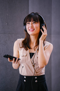 一位中年上镜的中国妇女在耳机上听音乐的画像