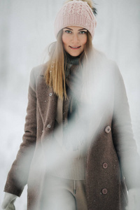 在冬林中散步时戴着帽子的快乐金发碧眼的女人的照片