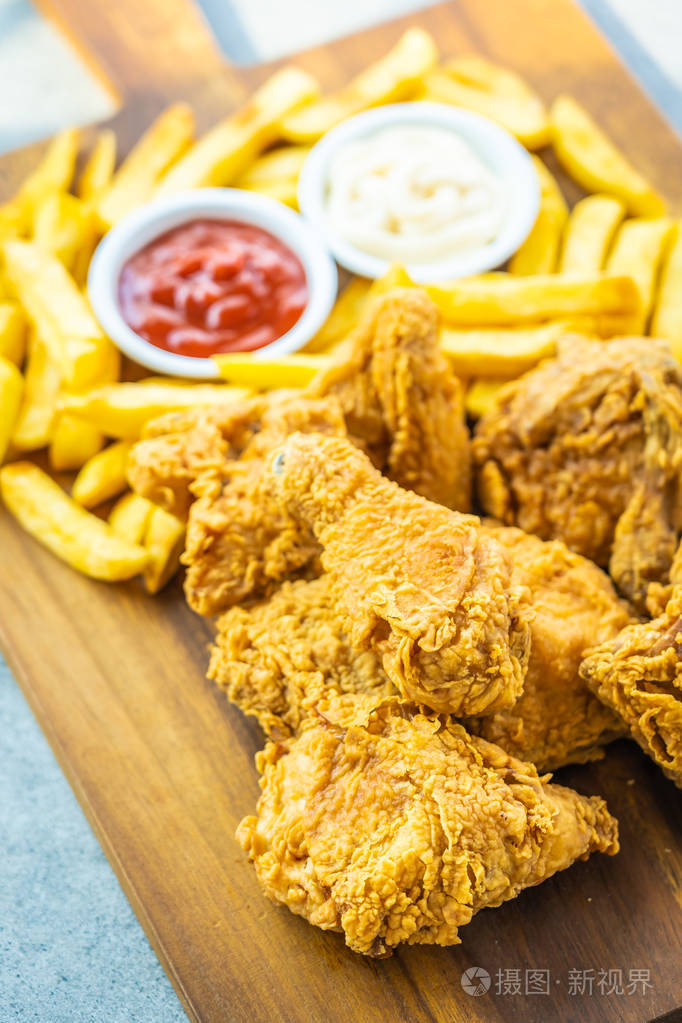 炸鸡翅炸薯条番茄酱蛋黄酱木切板上的炸鸡翅垃圾食品或不健康食品