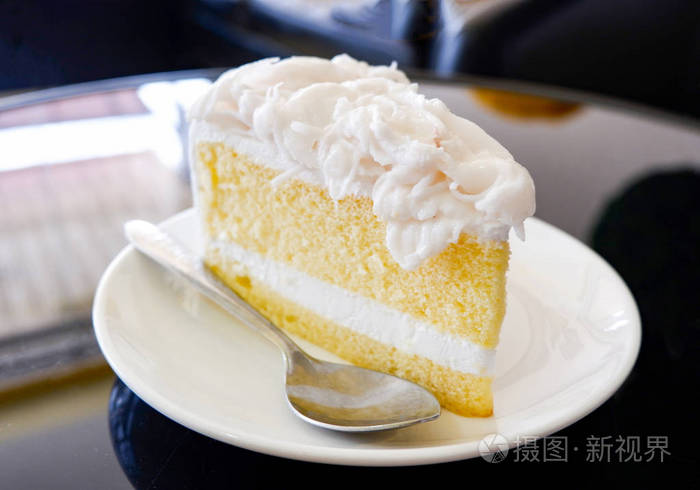 蛋糕片奶油香草蛋糕切片在白色盘子椰子蛋糕牛奶甜点在咖啡店的桌子上