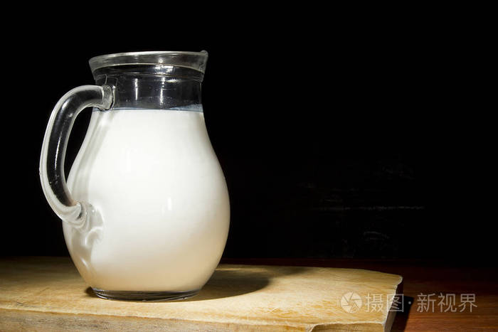 木桌上放着鲜牛奶的玻璃瓶