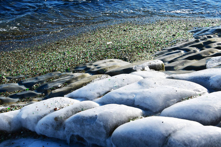 俄罗斯。 符拉迪沃斯托克海岸带着翡翠玻璃卵石和海岸上的一小卷水。 玻璃湾SteklyannayaKitobvaya冬季