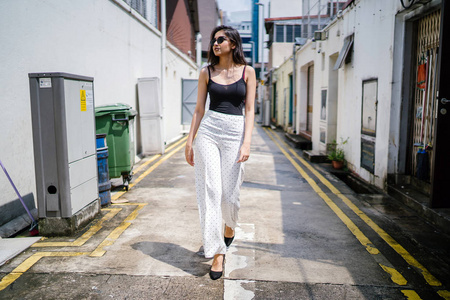 年轻高大苗条优雅的印度亚裔女性，穿着休闲装，白天走在亚洲街头的小巷里