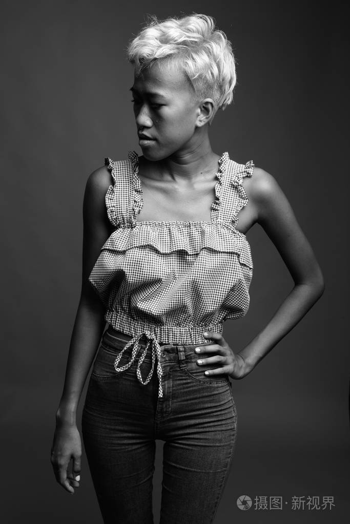 年轻美丽叛逆的女人短发对灰色的巴