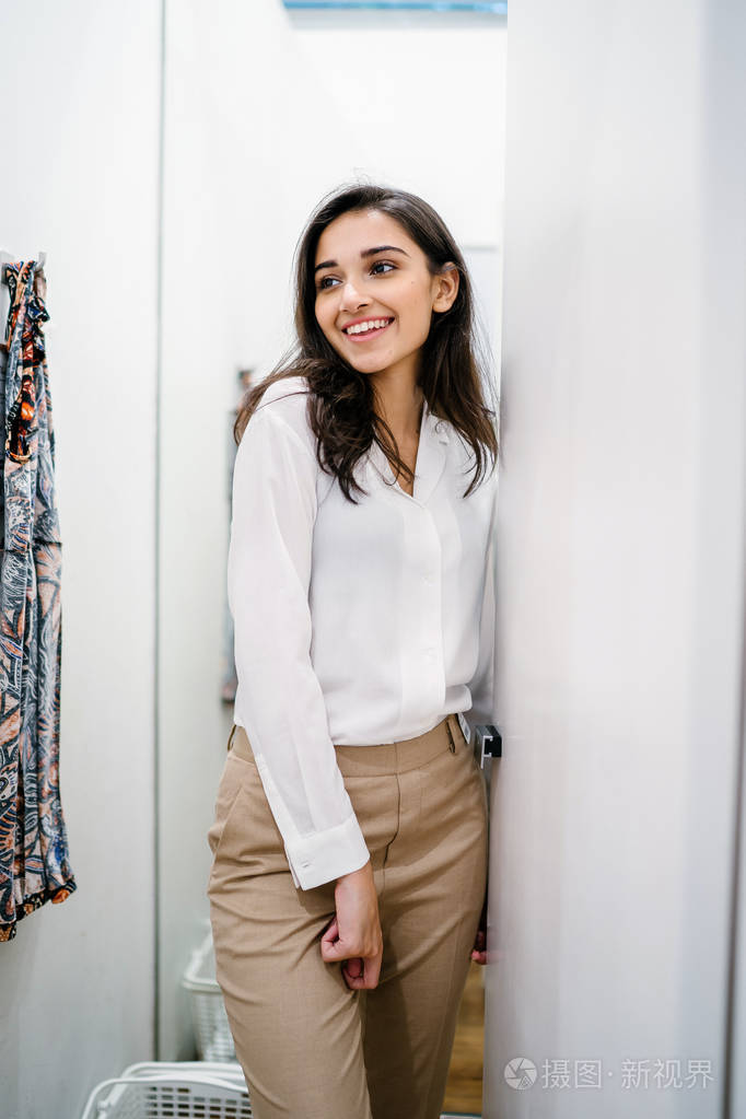 一位年轻美丽的印度亚裔妇女在商场时装店的试衣间试穿新衣服的肖像