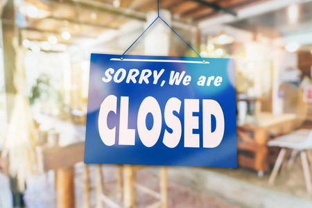 对不起我们关门了挂在有绿色背景的商店门口