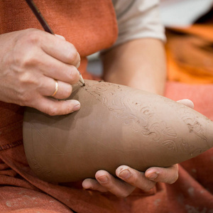 陶瓷车间，师傅把子放在未点燃的陶罐上..大师手的特写。手工制作，一种爱好。背景说明与粘土的手工工作。