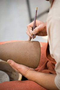 陶瓷车间，师傅把子放在未点燃的陶罐上..大师手的特写。手工制作，一种爱好。背景说明与粘土的手工工作。
