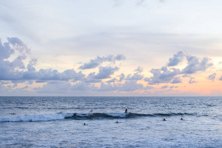 天空和海洋美丽的日落在海洋上。冲浪者在等海浪。