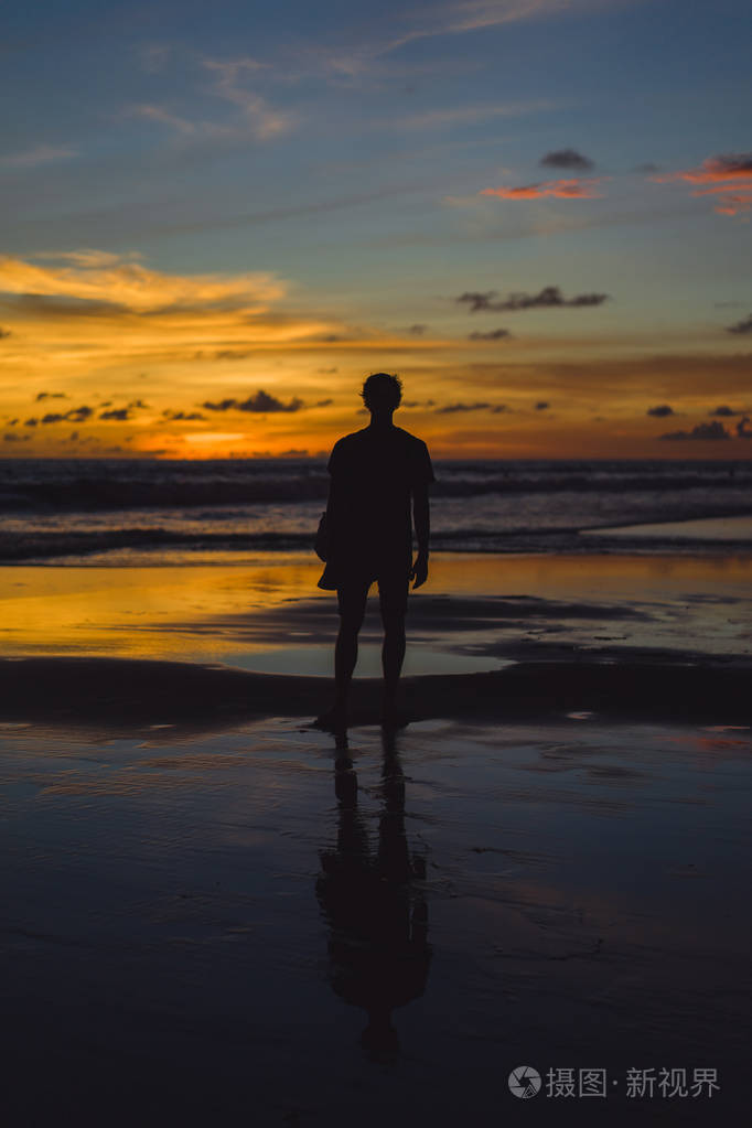 日落时海滩上的人那个女孩在夕阳的背景下跳跃