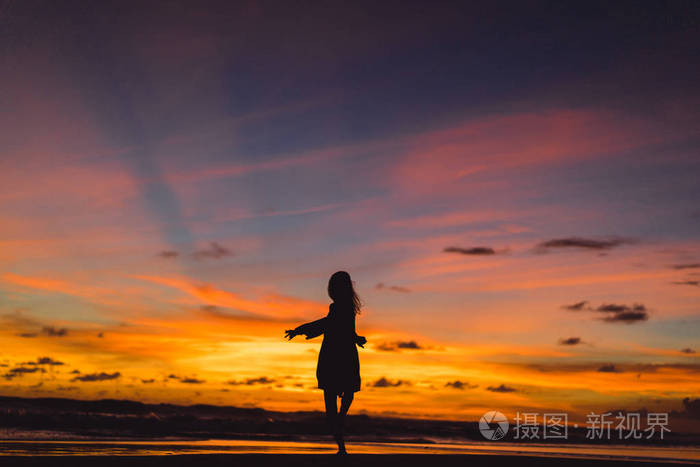 照片 日落时海滩上的人.那个女孩在夕阳的背景下跳跃.jpg