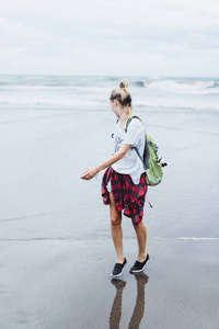 年轻漂亮的女人在沙滩上沿着海边散步