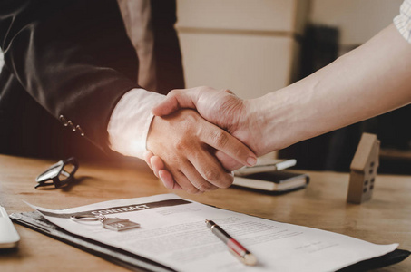 购房合同房地产经纪经理与青年客户签订购房合同后握手在房地产经纪