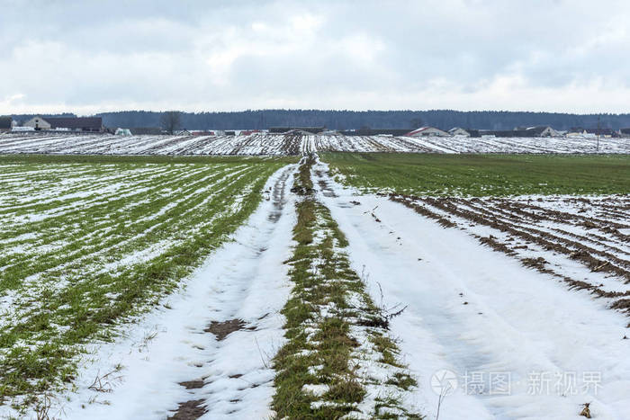 路上的水坑. 背景中的农场.欧洲冬天的开始.