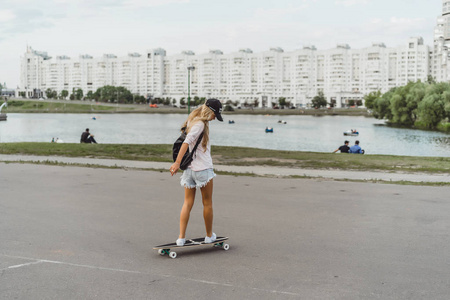 有长发的女孩在滑板上溜冰。 街头运动
