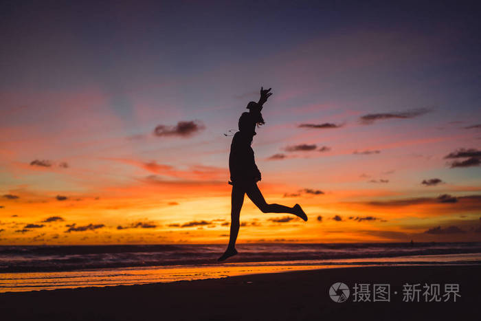 那个女孩在夕阳的背景下跳跃.