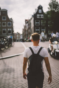 一个带背包的人走过阿姆斯特丹的街道。
