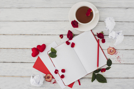 情人节。 笔记本在一张白色的木制桌子上，上面有红色的心。 情人节的浪漫早晨。 顶部视图