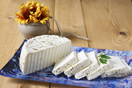 白色奶酪在木制背景上的蓝色盘子上。