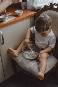 厨房里的小男孩帮妈妈做饭。 孩子参与烹饪。