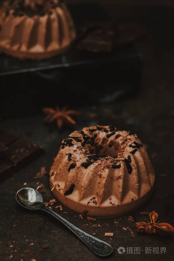 意大利甜点. 黑巧克力上的平底棉,黑色背景上有巧克力壶和巧克力洒