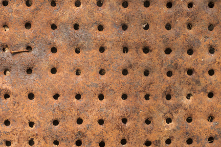 旧的生锈风化腐蚀的铁金属锡面，以孔洞特写为背景