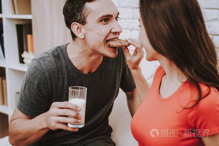 女人是个年轻的吃信. 男人拿着一杯牛奶. 人们互相看着对方.