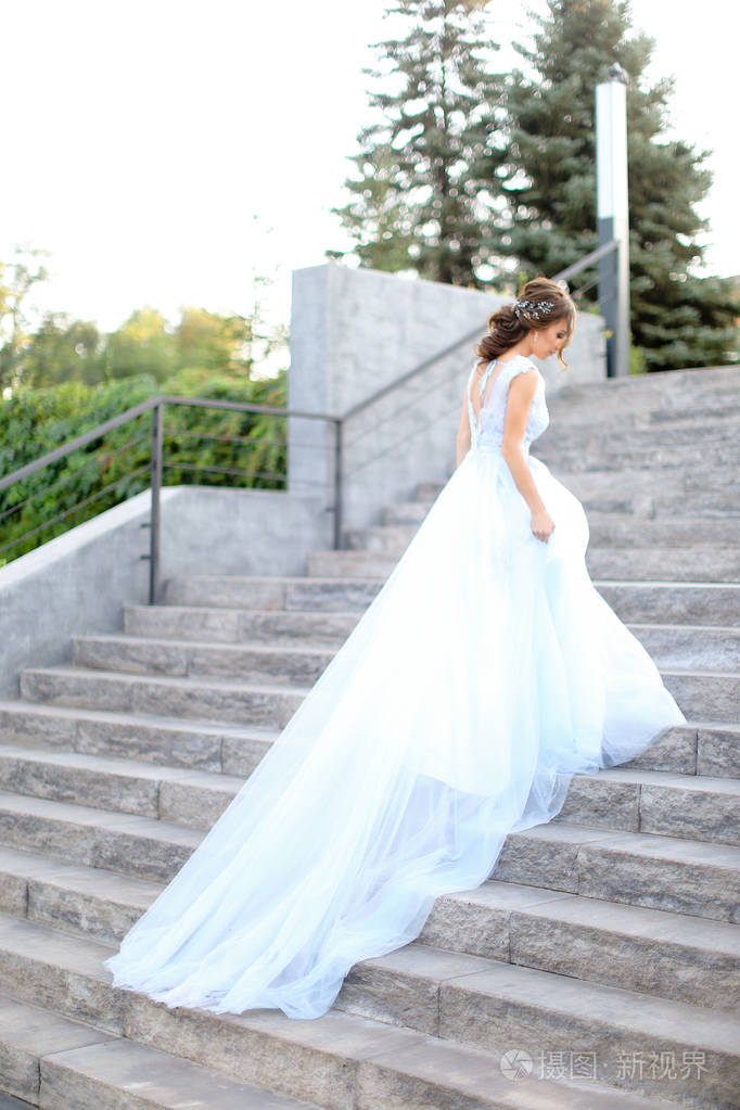 白种人未婚妻走在水泥楼梯上, 穿着白色礼服的背影的背面照片