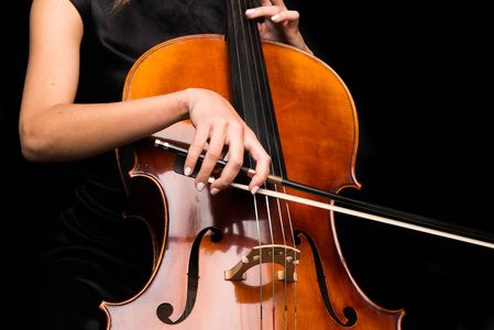 年轻女孩在黑色背景下玩大提琴