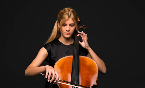 年轻女孩在黑色背景下玩大提琴