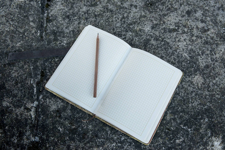 一支简单的铅笔放在一个石头表面的笔记本上