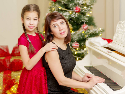妈妈和女儿在新的一年附近的白色钢琴