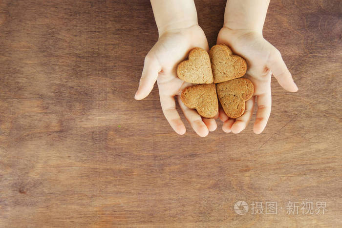 幼儿双手拿着烤饼干甜点饼干姜饼厨房里有木制背景关闭家庭假日休闲的