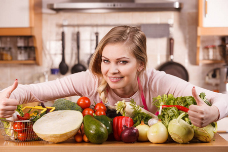 有趣快乐的年轻女人烹饪厨师有许多健康的蔬菜在桌子上。 西红柿洋葱生菜胡椒。 素食生活方式的概念。