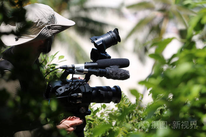 照片 摄影师或摄影师把摄像机放在山顶的三脚架上.