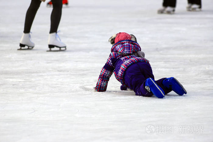 一个小男孩溜冰摔倒在冰上. 积极的家庭运动寒假和寒冷的季节.