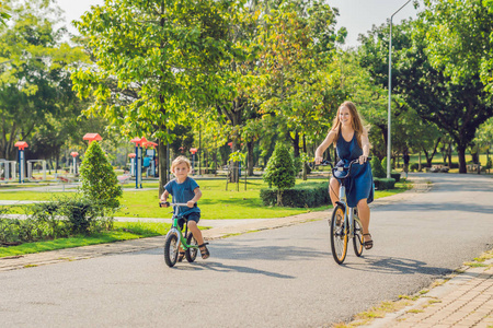 幸福的家庭是骑自行车在户外和微笑。一辆自行车，在 balancebike 上的儿子的妈妈