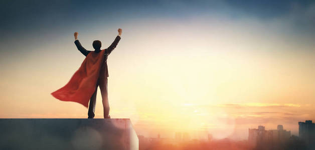 超级英雄商人在日落时看城市天际线。 成功领导和商业胜利的概念。